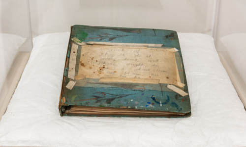 Photograph of one of Henry Darger's scrapbooks, blue with a handwritten note on the cover