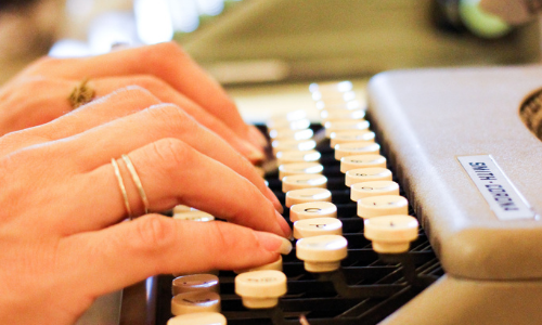 Photograph of a woman's hands typing on a typewriter