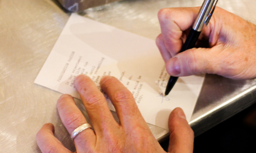 Photograph of a man's hands signing a typed poem
