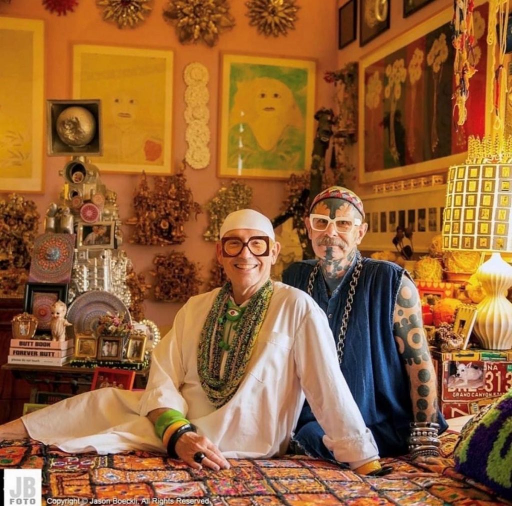 Photograph of Rob and Orren, sitting in their home with their art collection surrounding them