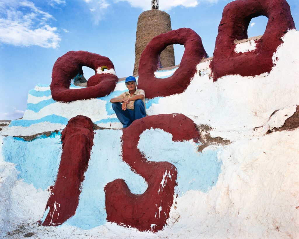 Leonard Knight perches at the top of the “God is Love” centerpiece of Salvation Mountain outside of Niland, California