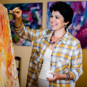 Photo of a woman, identified as Irina Gorbman, wearing a yellow plaid shirt, painting